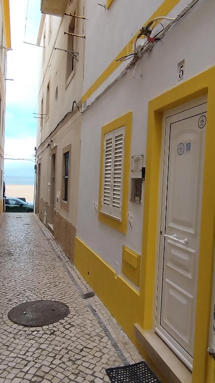 a yellow and white building with a door and a street at Casa da Liberdade em Nazaré in Nazaré