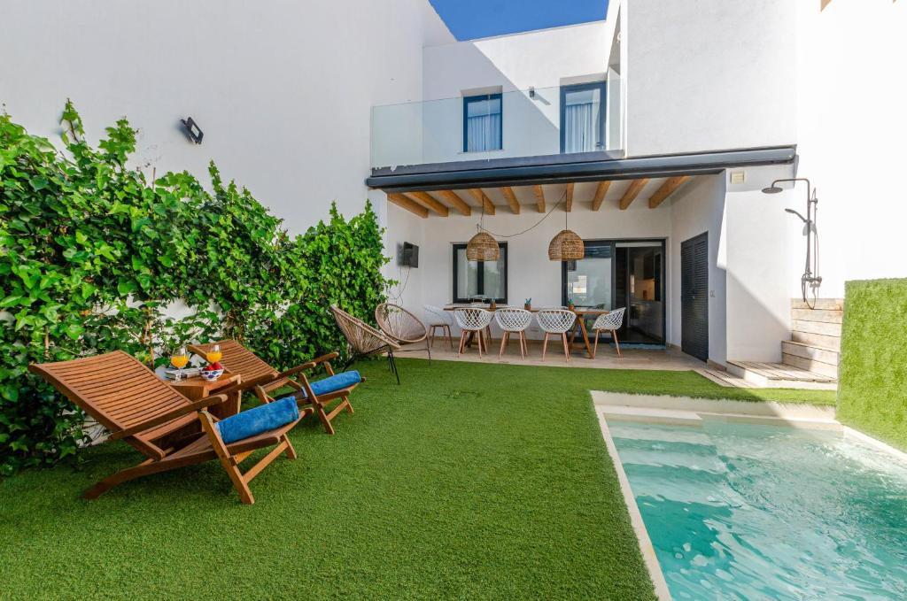 a backyard with a table and chairs and a swimming pool at YourHouse Els Nins villa in Can Picafort