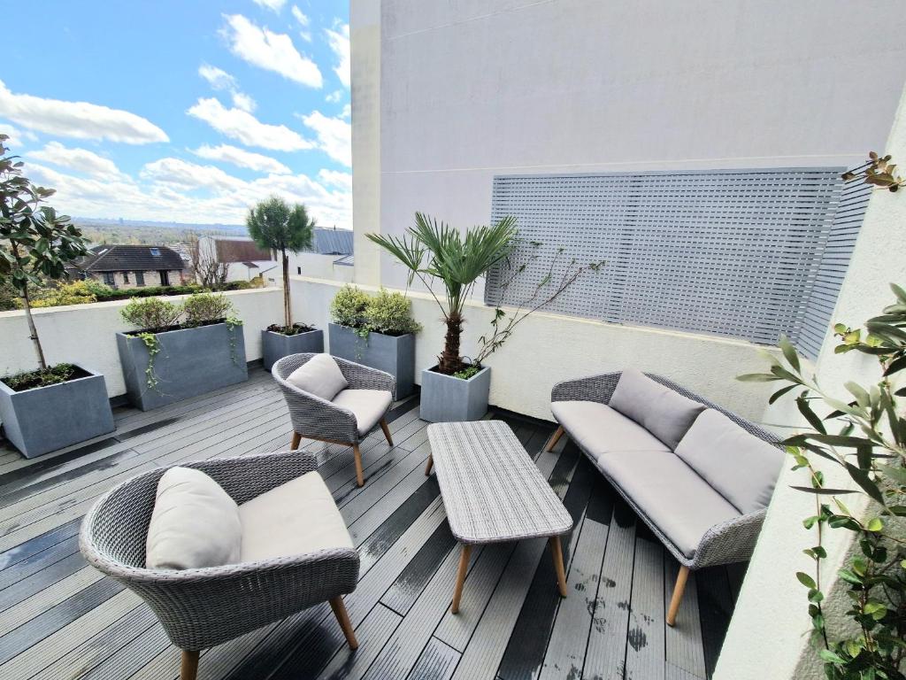 a patio with chairs and tables on a balcony at Le Rooftop Suresnes Paris La Défense - Spacieux Duplex 100 m2 Terrasse in Suresnes