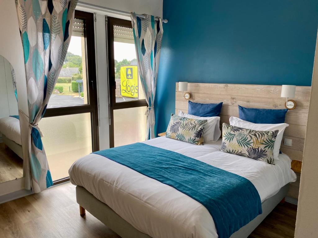 een slaapkamer met een bed met blauwe muren en een raam bij Logis Hotel Restaurant l'Orée Des Bois in La Breille-les-Pins