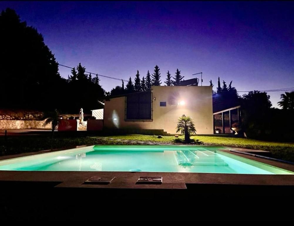 una piscina di fronte a una casa di notte di Strelitzia's house with pool, parking & wi-fi ad Avola