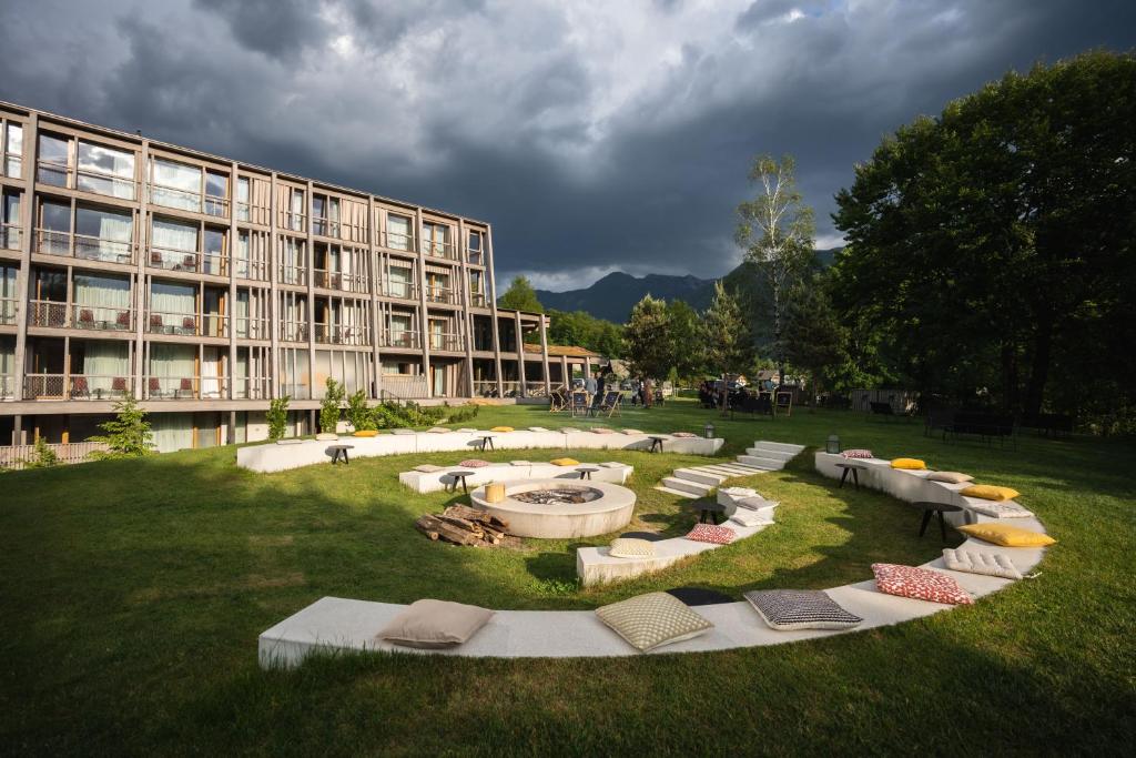a building with a courtyard with a fire pit in the grass at Hotel Bohinj in Bohinj