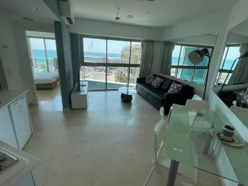 ein Wohnzimmer mit einem Sofa und einem Glastisch in der Unterkunft מלון דירות אוקיינוס במרינה דירות עם נוף לים in Herzliya B
