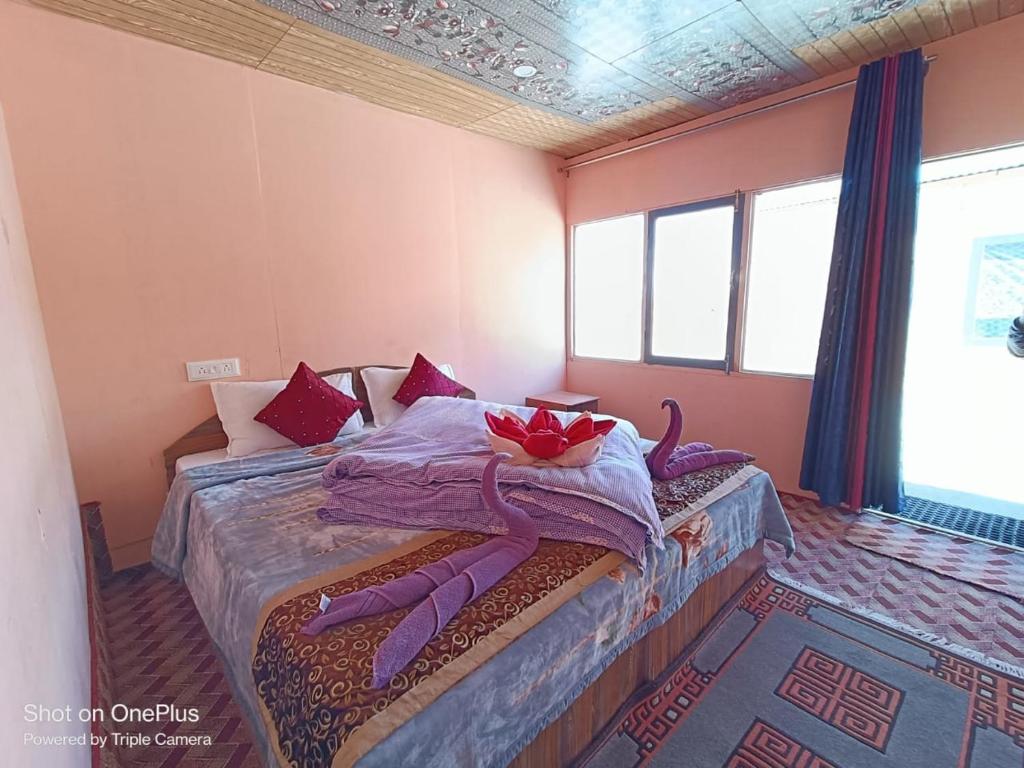 a bedroom with a bed with purple sheets and red pillows at Wanderlust Cottage Pangong Lake, Lukung, in Lukung