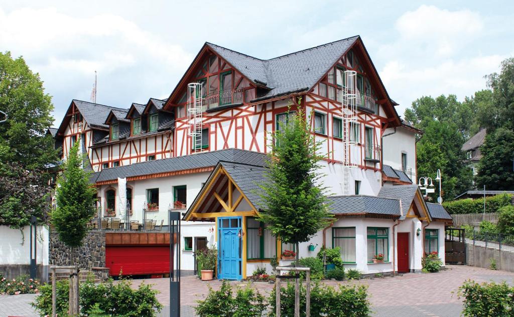 une grande maison en bois avec une porte bleue dans l'établissement Hotel Westerwälder Hof, à Bad Marienberg