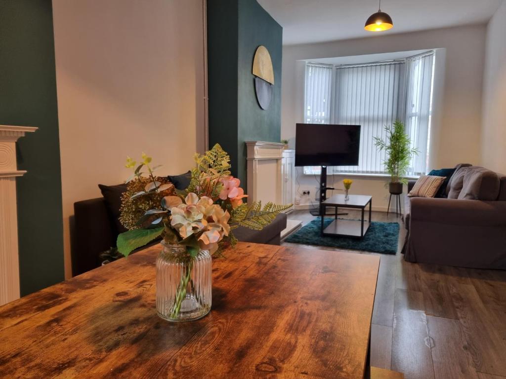 a vase of flowers on a wooden table in a living room at Spacious 3 bedroom house near city centre & docks/free parking in Liverpool