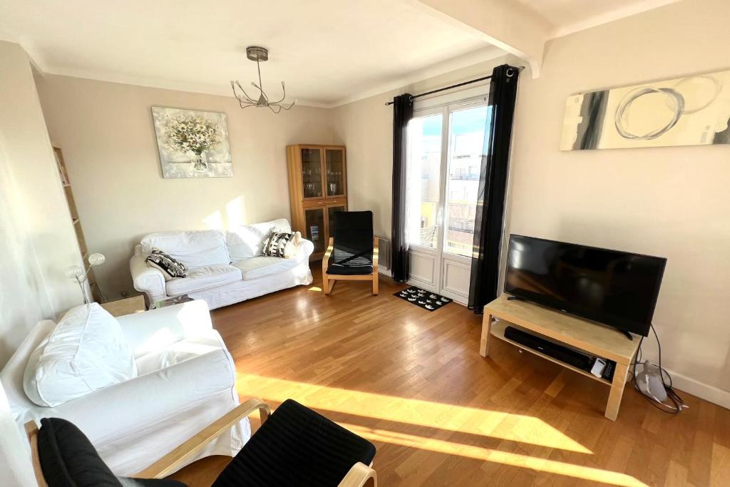 ein Wohnzimmer mit einem weißen Sofa und einem TV in der Unterkunft Juan les pins centre ville - 4 personnes - dernier étage in Antibes