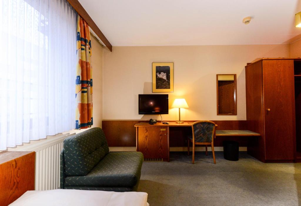 a hotel room with a couch and a desk with a television at APPART-HÔTEL MARCO POLO in Luxembourg