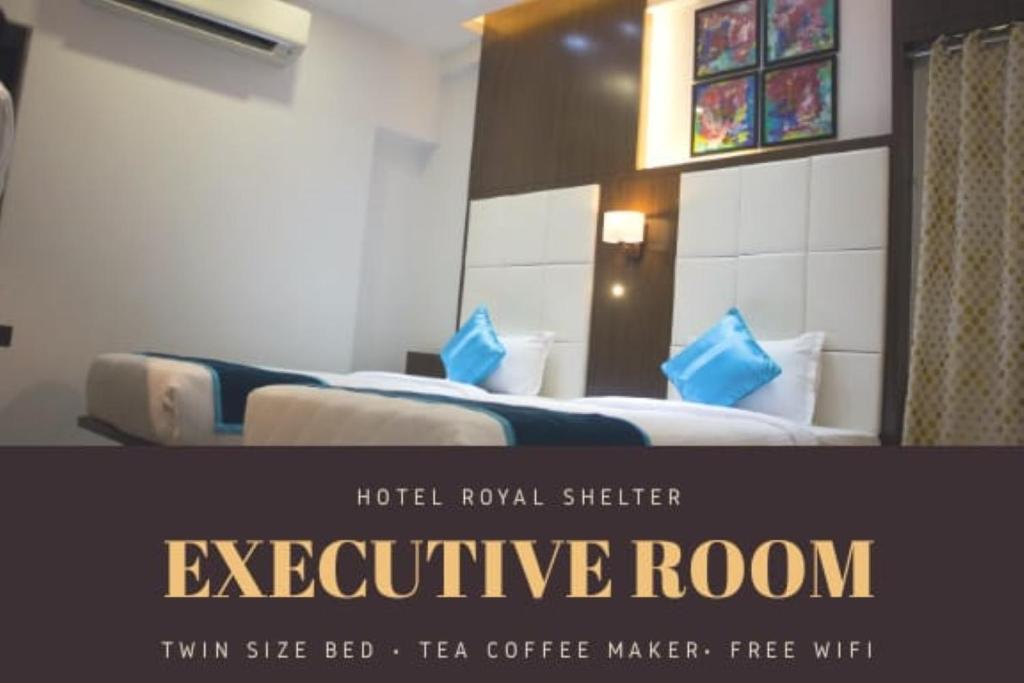 Hotel Royal Shelter Vapi في فابي: غرفة فندق بسريرين مع وسائد زرقاء