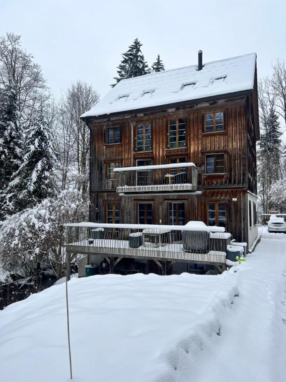 ein Blockhaus im Schnee mit einer Bank in der Unterkunft Alpen Oase Natur in St. Gallen