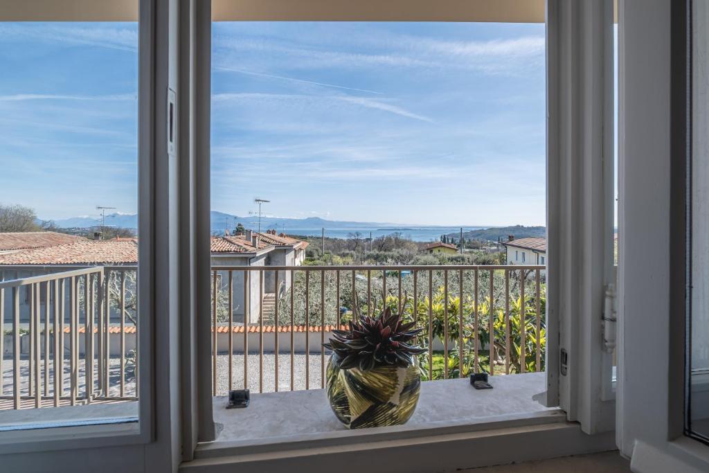 ein Fenster mit Blick auf einen Balkon mit Topfpflanze in der Unterkunft Il lago dei Sogni - Stupenda Vista Lago e Colline in Barcuzzi