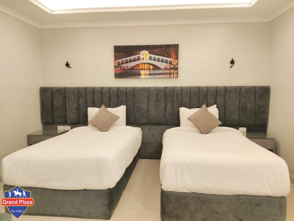 Grand Plaza Sheikh Zayed في Kafr Abū ʼumaydah: سريرين في غرفة الفندق ذات شراشف بيضاء