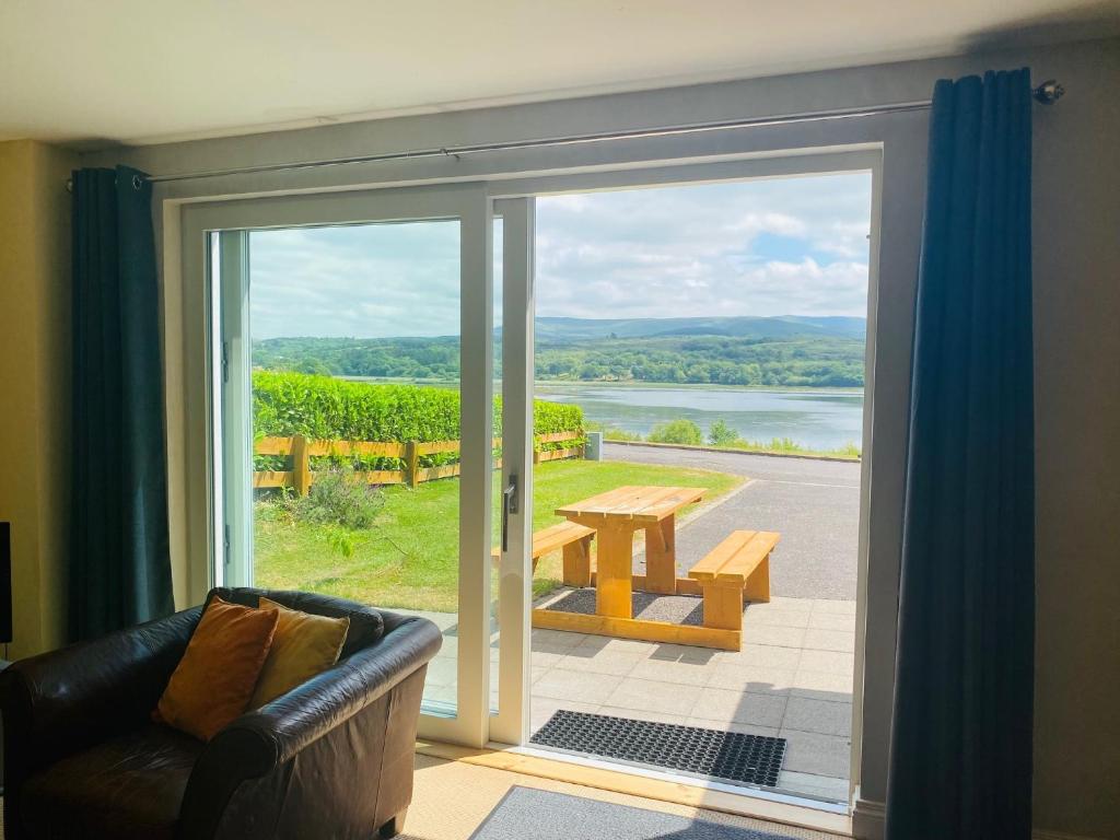 a living room with a sliding glass door to a patio at 3 bedroomed house with view of Kenmare Bay Estuary in Kenmare