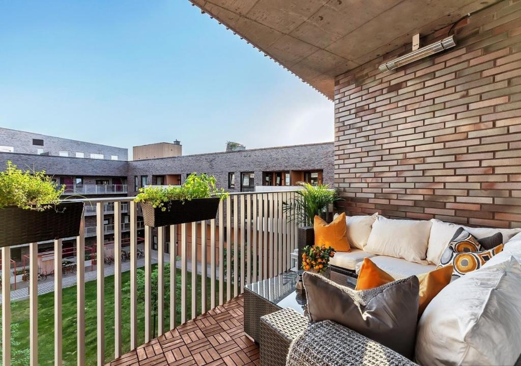 a patio with a couch and a brick wall at Seaside apt - 2 sunny balconies - Modern - 5 pax in Oslo