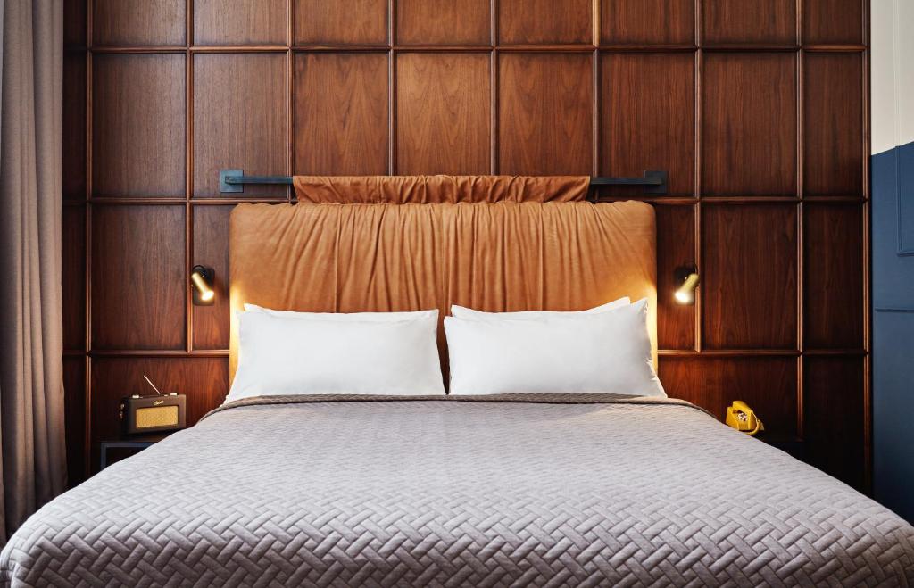 a bedroom with a large bed with a wooden headboard at The Hoxton, Amsterdam in Amsterdam