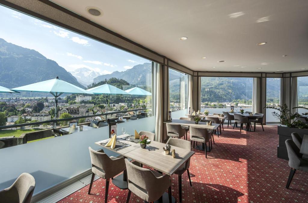 een restaurant met tafels en stoelen en uitzicht op de bergen bij Metropole Swiss Quality Hotel in Interlaken