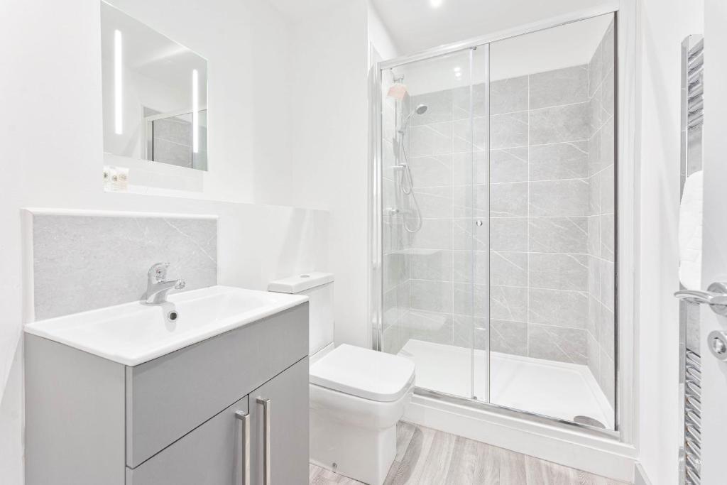 a white bathroom with a toilet and a shower at Modern and Bright 2 Bed Apartment in Redditch in Redditch