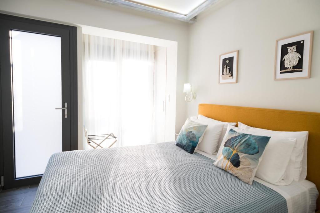 Un dormitorio con una cama con almohadas blancas y una ventana en Gruccio Yellow Studio - A Sunny Skiathos Gem, en Skiathos