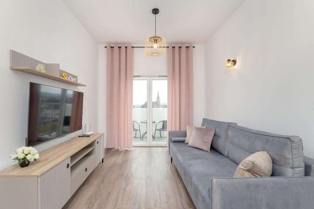 a living room with a gray couch and a television at Cosy Apartment with Balcony in Rzeszów by Renters in Rzeszów