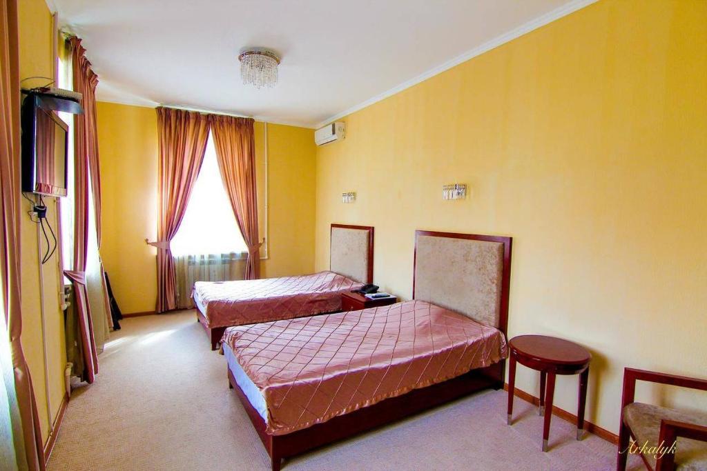 Duas camas num quarto com paredes amarelas em гостиница Аркалык em Arqalyq
