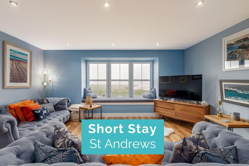 a living room with blue walls and a flat screen tv at Golf Course View Apartment - Craighead - Crail in Crail