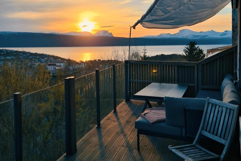 a deck with a table and a chair and a sunset at Luxury Mountain Apt with Sauna in Narvik