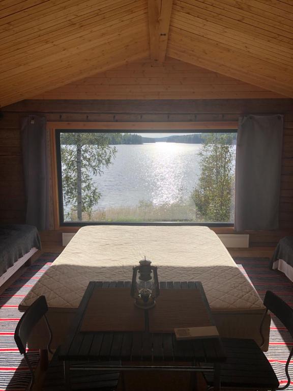 ein Schlafzimmer mit einem Bett und einem großen Fenster in der Unterkunft Vehkaniemen Lomatila in Pohjaslahti