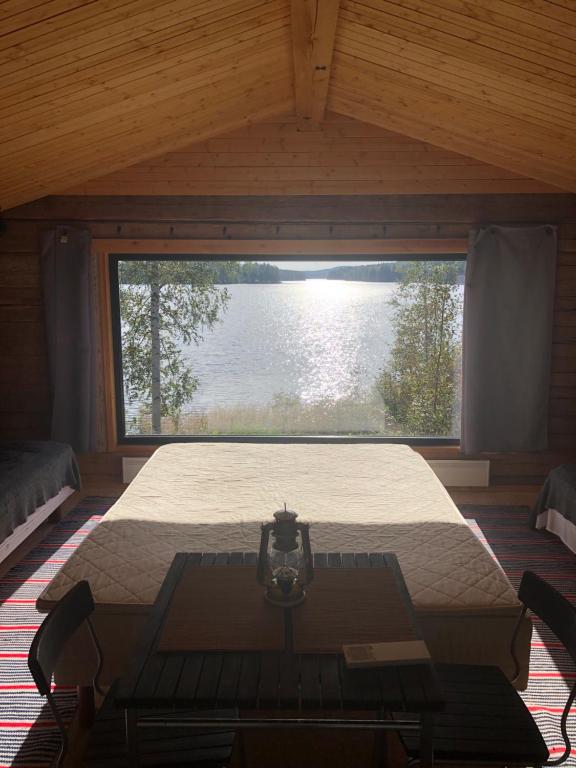 a bedroom with a bed and a large window at Vehkaniemen Lomatila in Pohjaslahti