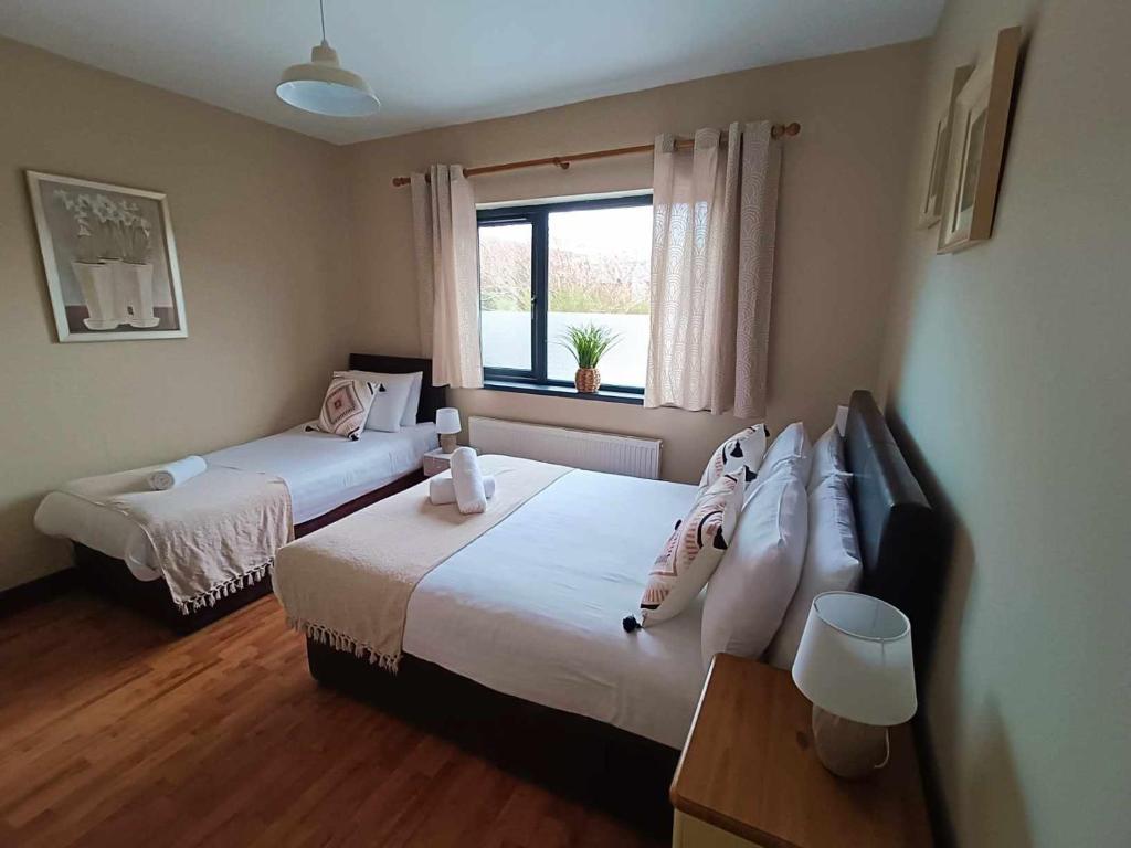 1 dormitorio con 2 camas y ventana en Dingle Atlantic Lodge B&B, en Dingle