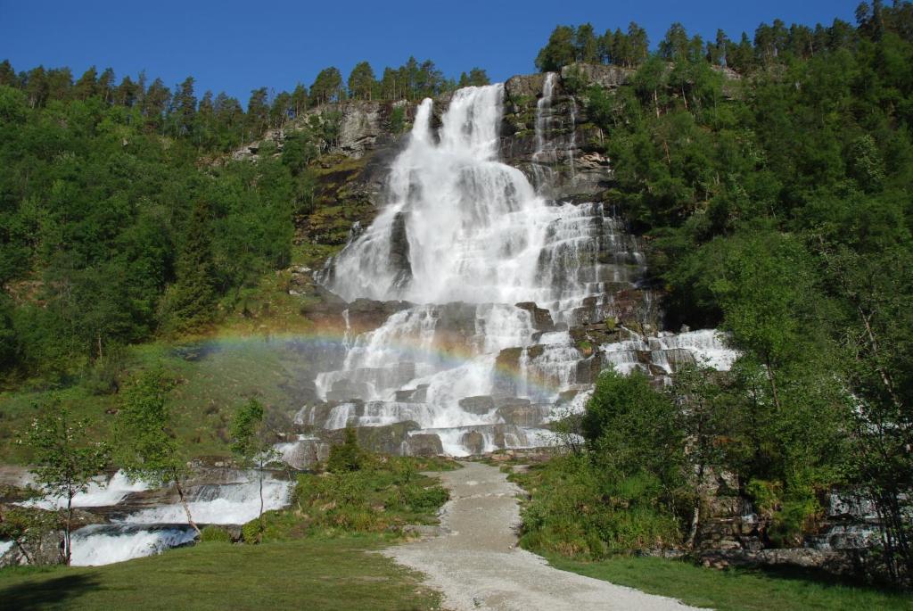 un arcobaleno di fronte a una cascata su una montagna di Tvinde Camping a Skulestadmo