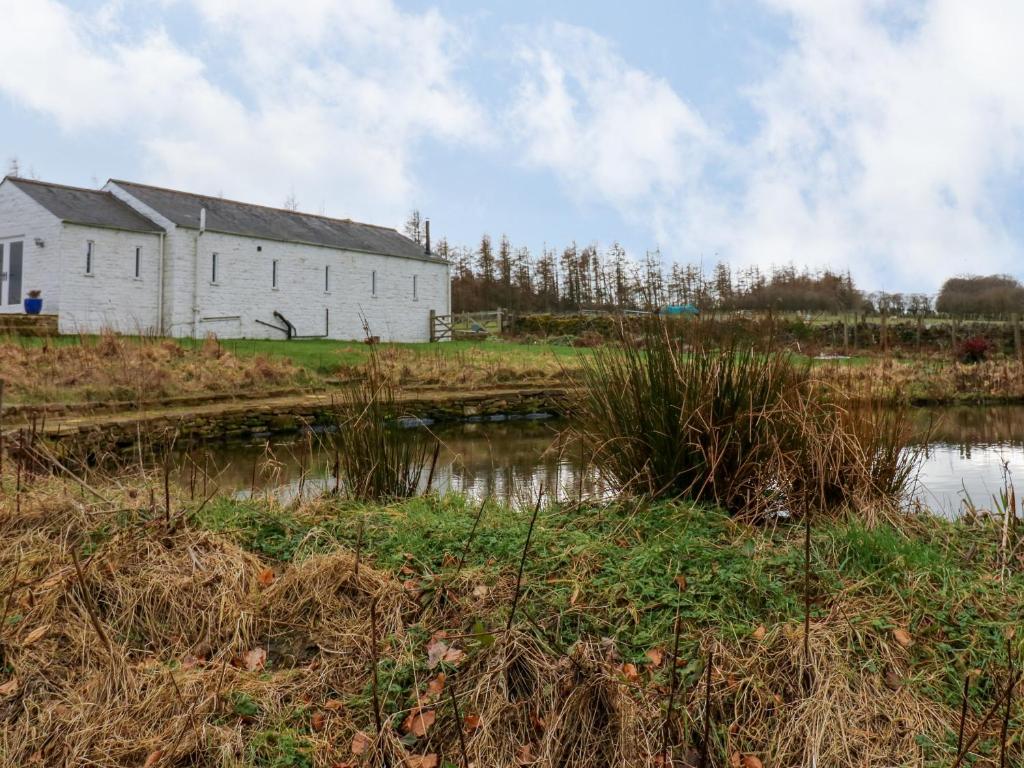 a building in a field next to a body of water at The Barn in Bishop Auckland