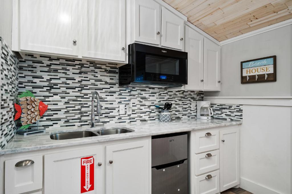 a kitchen with white cabinets and a sink and a microwave at Tranquil Cove in Port Aransas