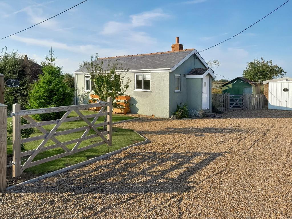 a house with a gate in front of a driveway at Curlew Cottage in Thorpe Saint Peter