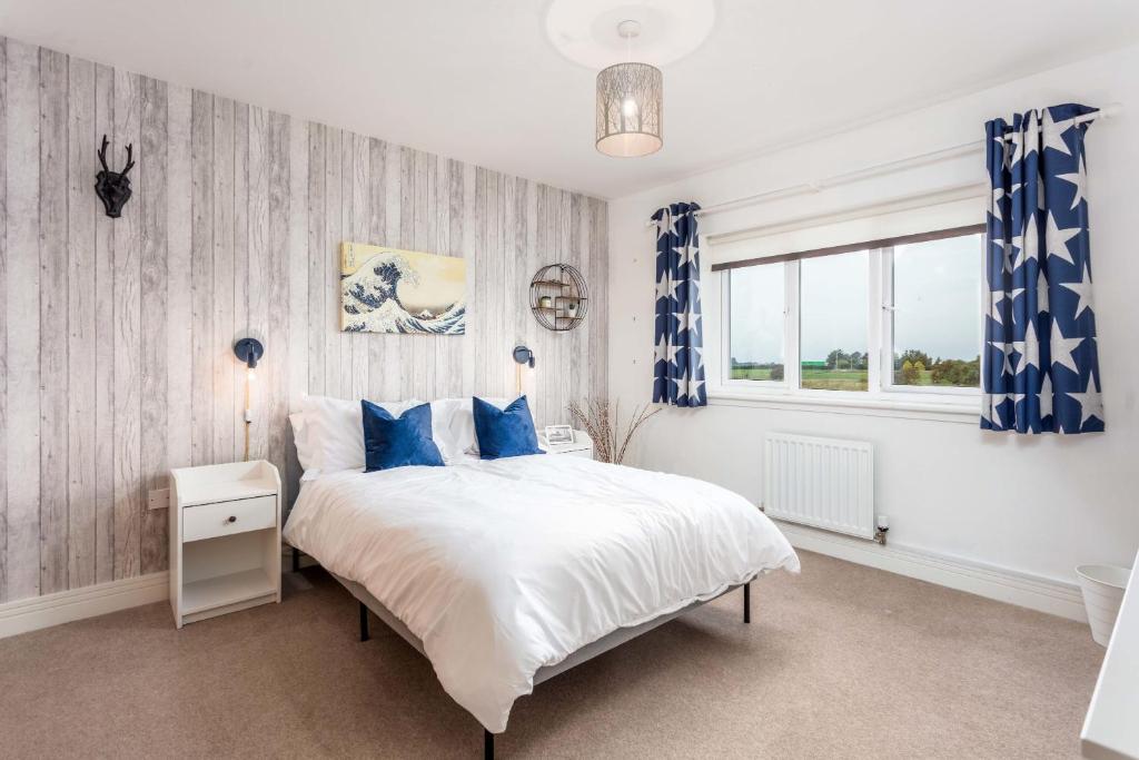 a bedroom with a large bed with blue curtains at 52 Hannah Wynd in Ayr