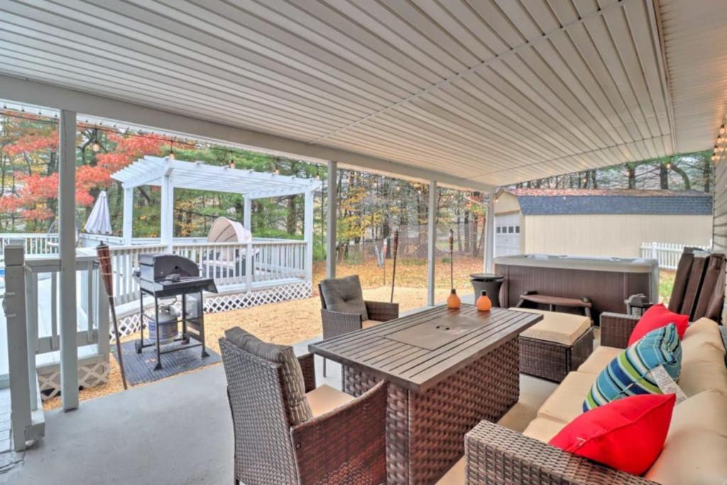 eine Terrasse mit einem Tisch, Stühlen und einem Grill in der Unterkunft Oasis Hot Tub Pool Game Room in Saylorsburg