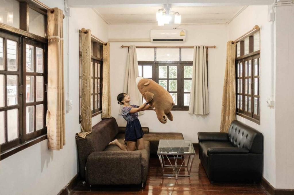 Una ragazza che tiene un orso di peluche sul divano di บ้านพักเหมาหลังเชียงคาน ฮักเลย ฮักกัญ โฮมสเตย์ 1 - ຊຽງຄານ ຮັກເລີຍ ຮັກກັນ ໂຮມສະເຕ1 -Chiang Khan Hugloei HugKan Homestay1 a Chiang Khan