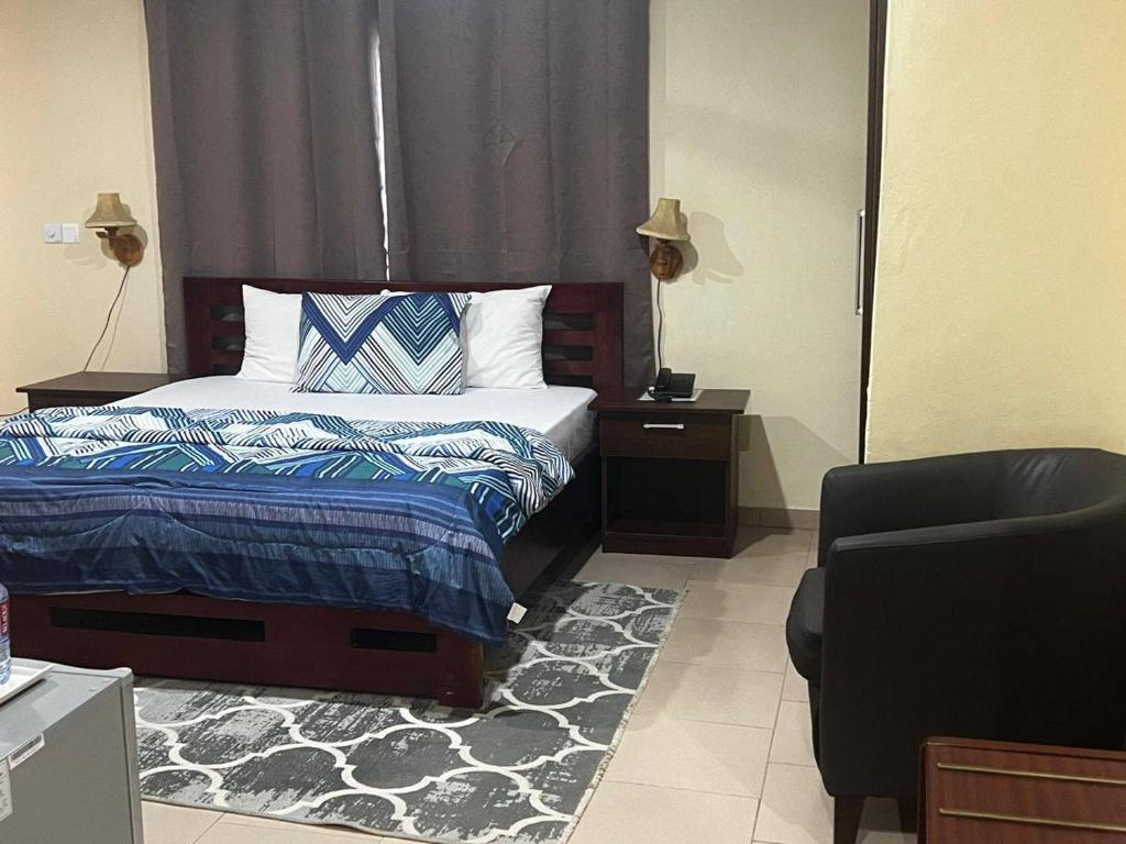 1 dormitorio con cama, silla y espejo en Amoaba's Inn, en Akropong