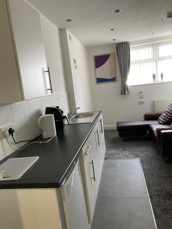 a kitchen with a sink and a living room at Palatine Aparthotel in Liverpool