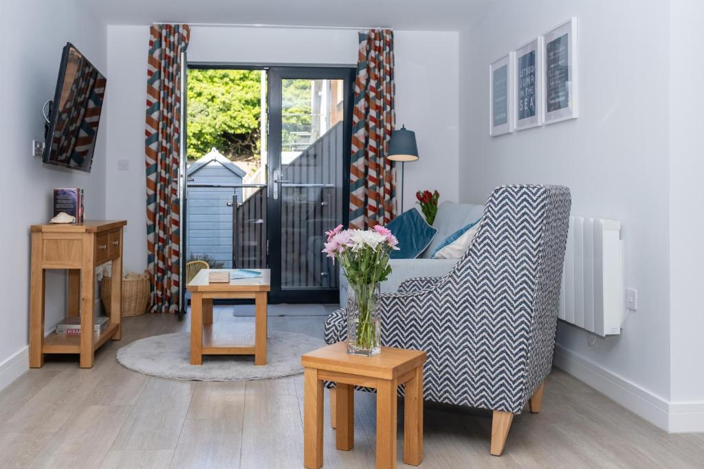 a living room with a chair and a vase of flowers at 2 Rockham - Luxury Apartment at Byron Woolacombe, only 4 minute walk to Woolacombe Beach! in Woolacombe