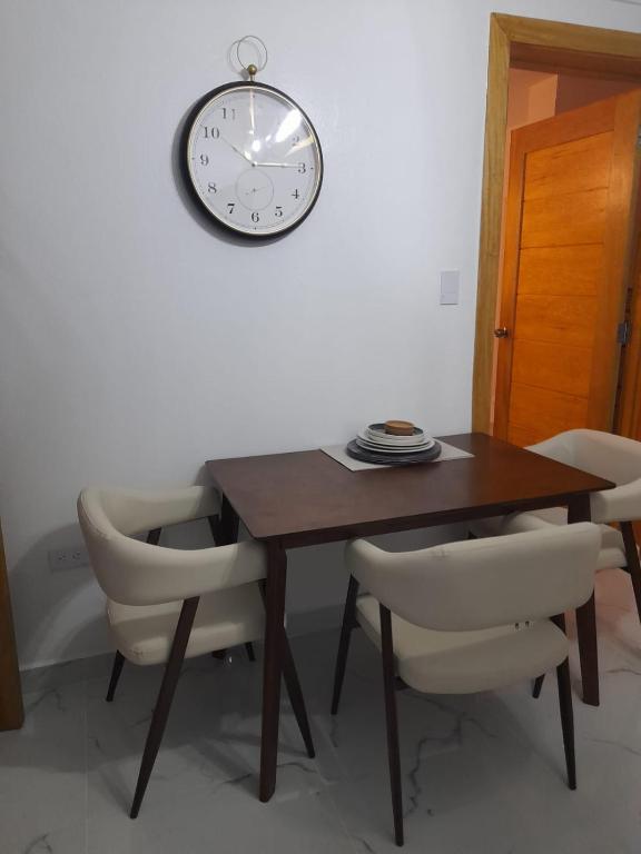 mesa de comedor con sillas y reloj en la pared en Apartamento centro de la ciudad 2 en San Pedro de Macorís