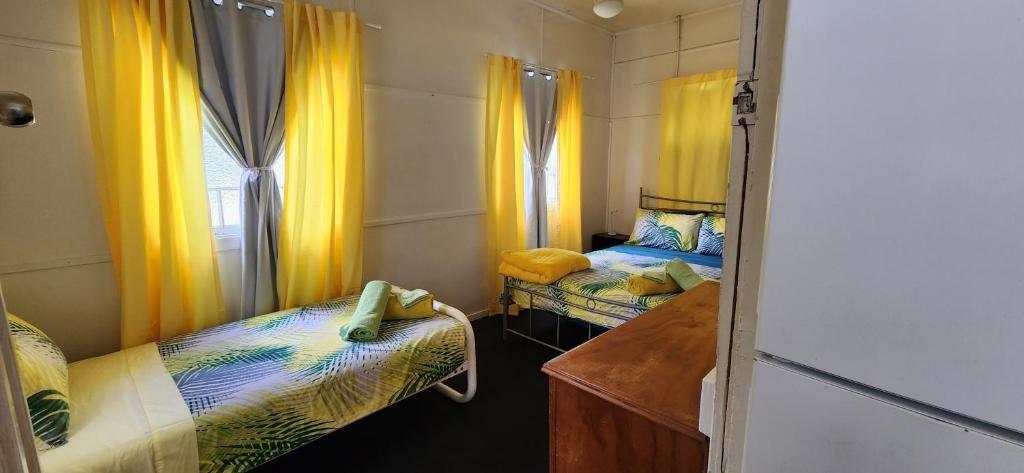 two beds in a room with yellow curtains at Meyenburg Unit 1 in Mount Morgan