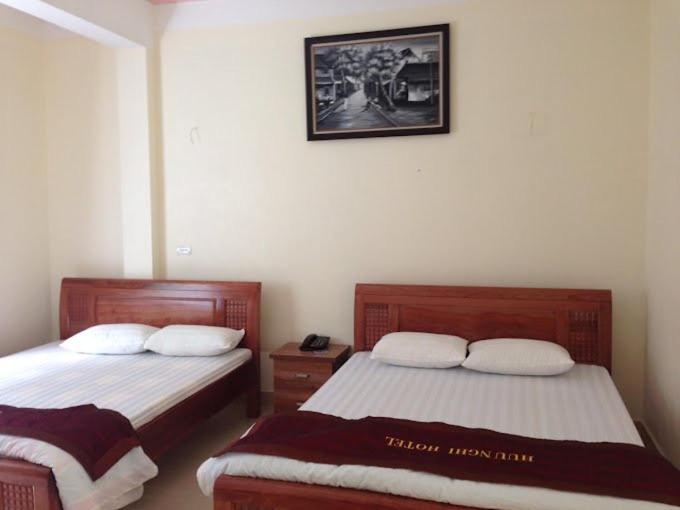 - une chambre avec 2 lits et une photo sur le mur dans l'établissement Nhà nghỉ Minh An, à Diện Biên Phủ