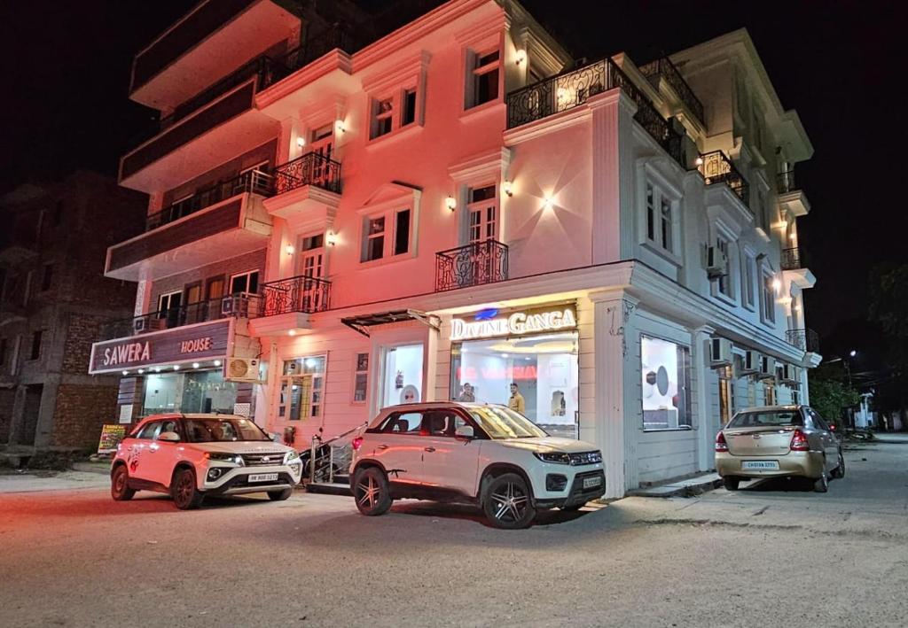 deux voitures garées devant un bâtiment rose dans l'établissement The Deviine Ganga - Haridwar, à Haridwar