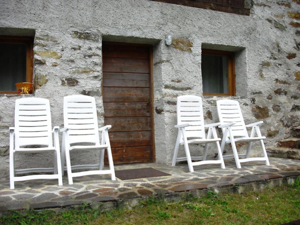 quatro cadeiras brancas sentadas fora de um edifício em Baita Misseroni Trilocale em Rabbi