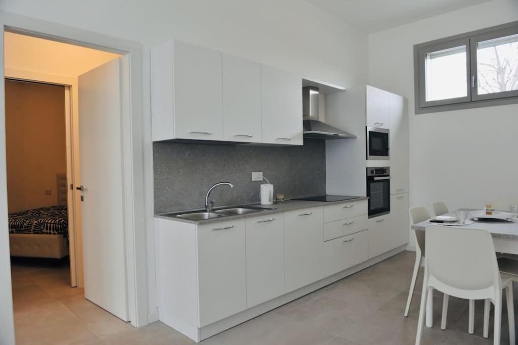 uma cozinha branca com um lavatório e uma mesa em Appartamento Medea em Cavernago