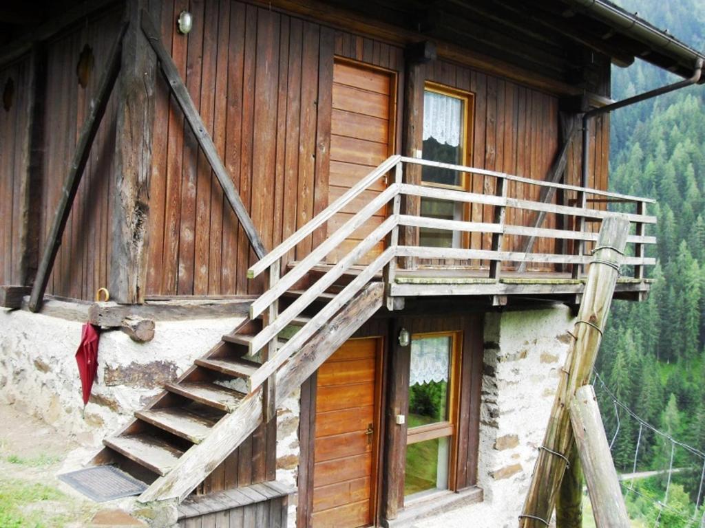 Una casa de madera con una escalera en el lateral. en Baita Misseroni Quadrilocale, en Rabbi