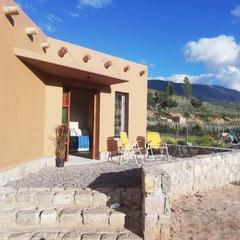 a house with yellow chairs and a stone wall at Cabaña Huacalera in Huacalera