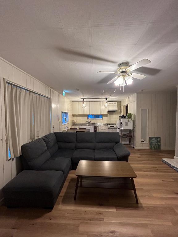 uma sala de estar com um sofá e uma ventoinha de tecto em ライフタイムハウス55 em Furugen