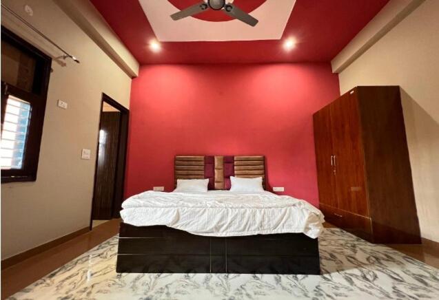 ノイダにあるOYO The Golf Star Near Pvr Ansal Plaza Greater Noidaの赤い壁のベッドルーム1室(大型ベッド1台付)