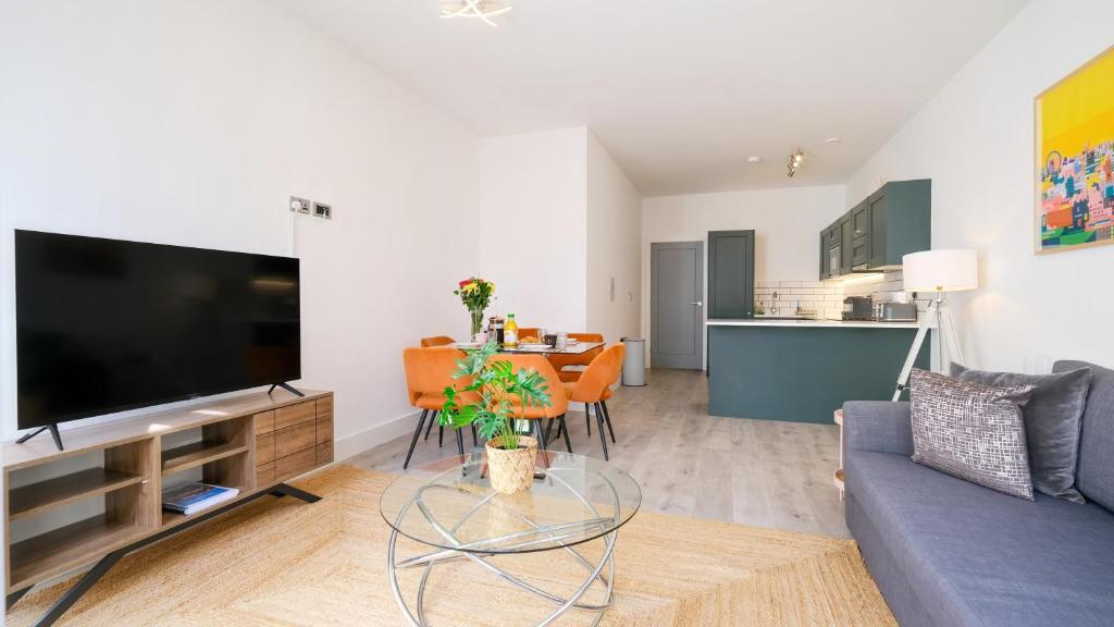 a living room with a couch and a table with a tv at Stunning Acton Apartment With Patio in London